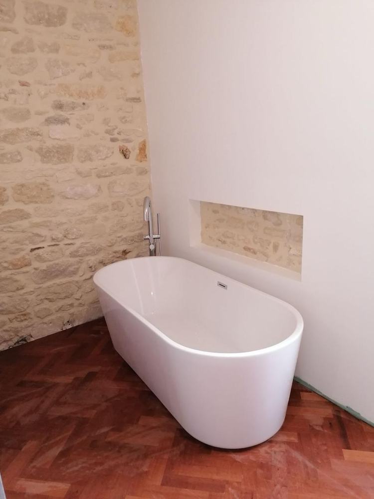 Baignoire îlot installée dans une longère en pierre, plomberie de rénovation en Charente-Maritime
